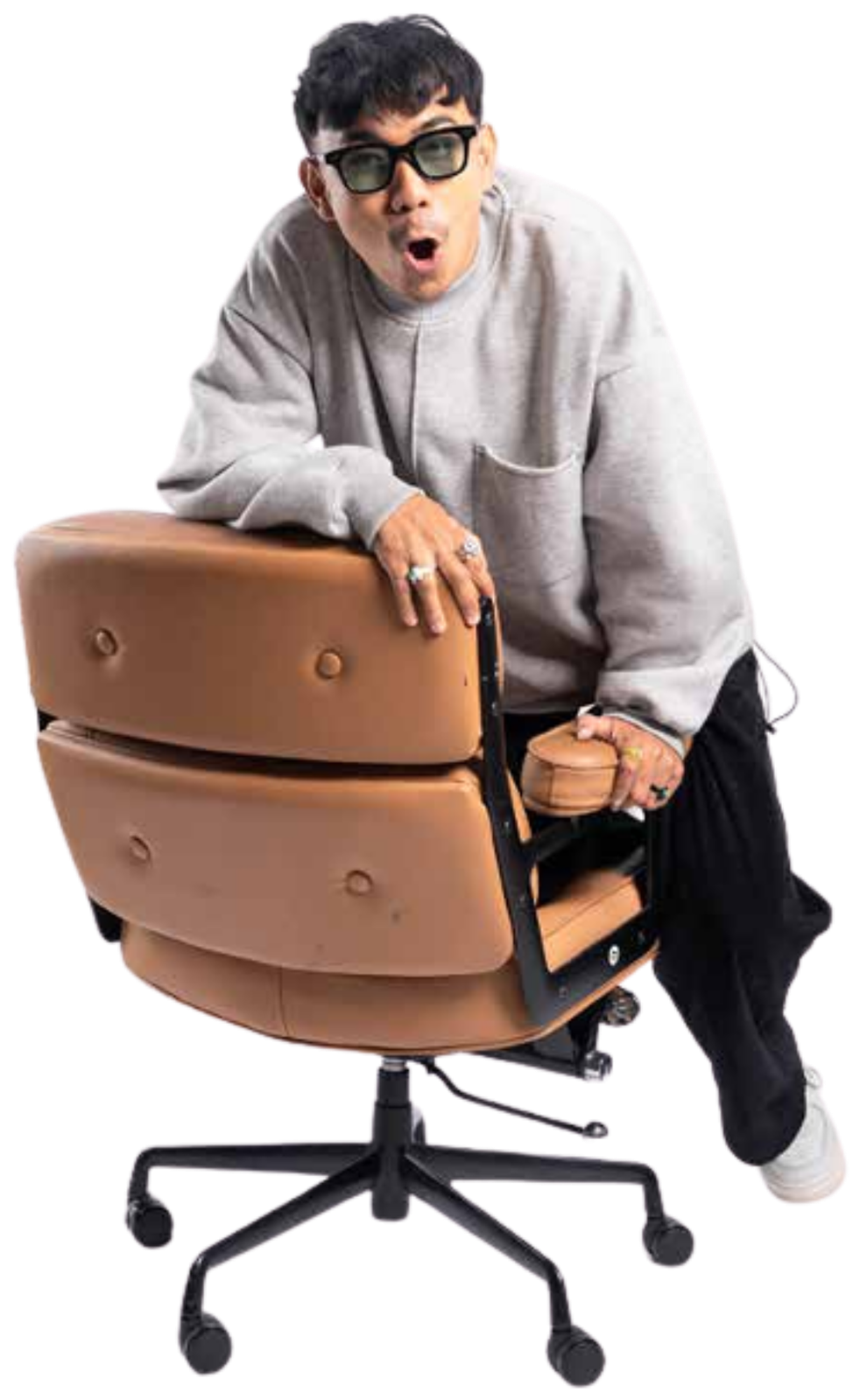 Yudha Bhaskara leaning playfully over a brown studio chair